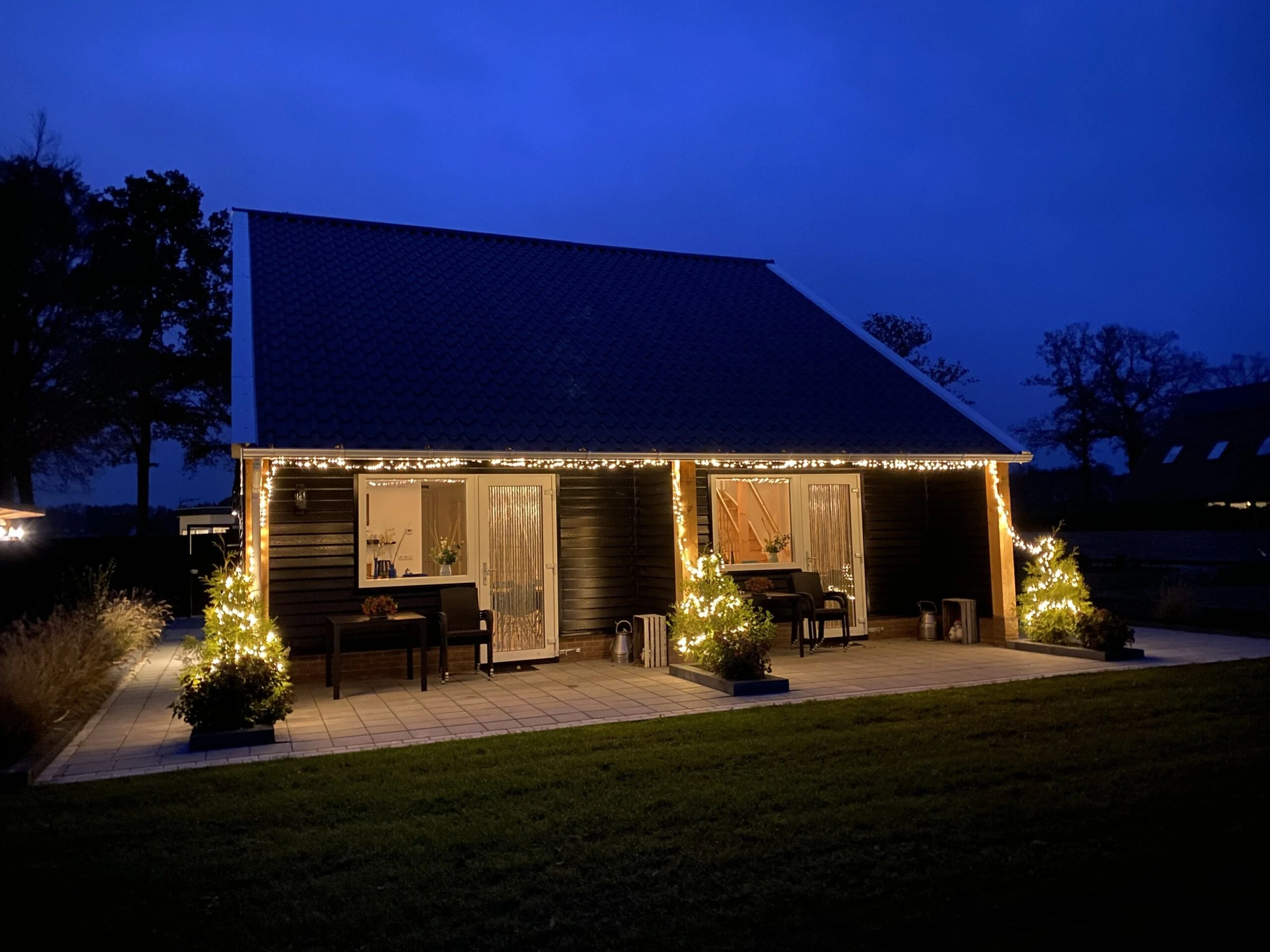 De kapschuur ’s avonds, met lichtjes langs de twee terrassen