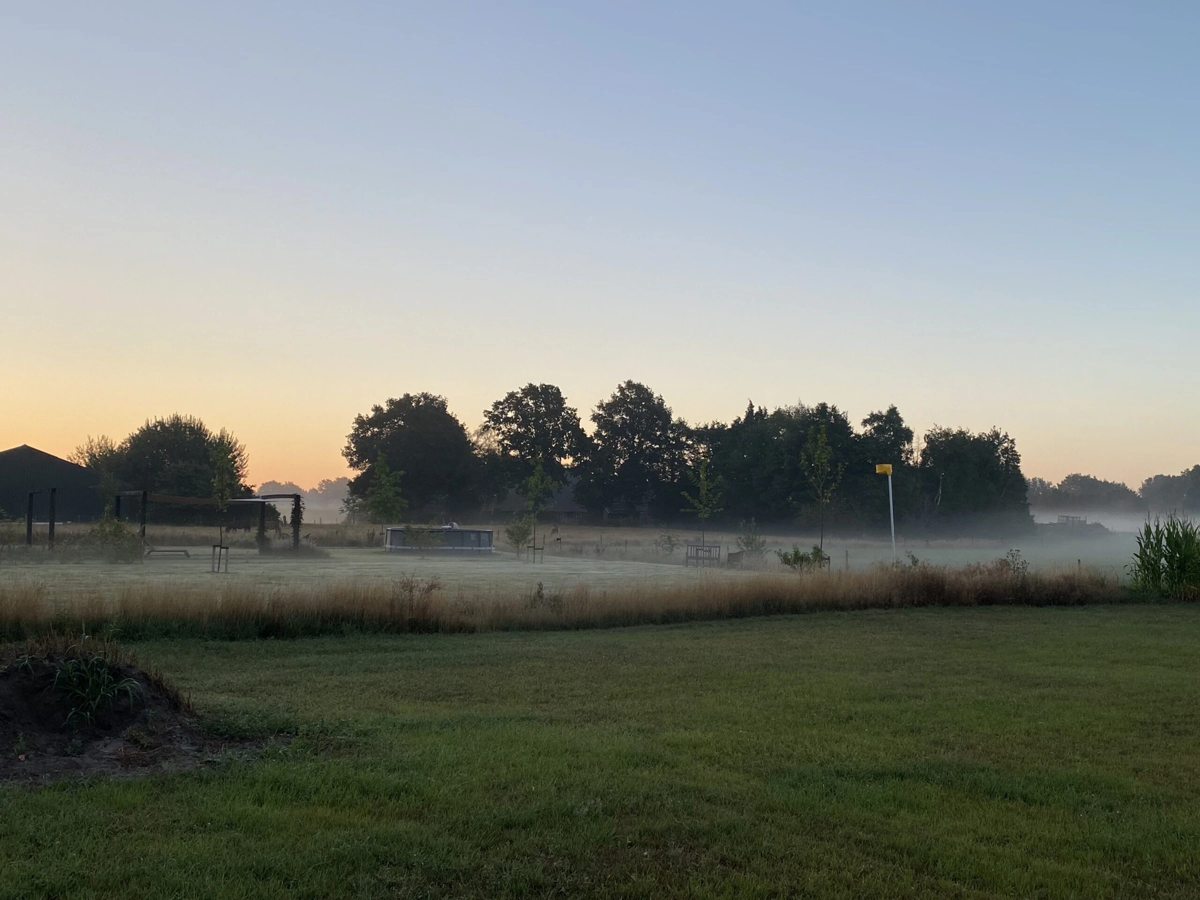 Zonsopkomst boven de weilanden achter het huisje